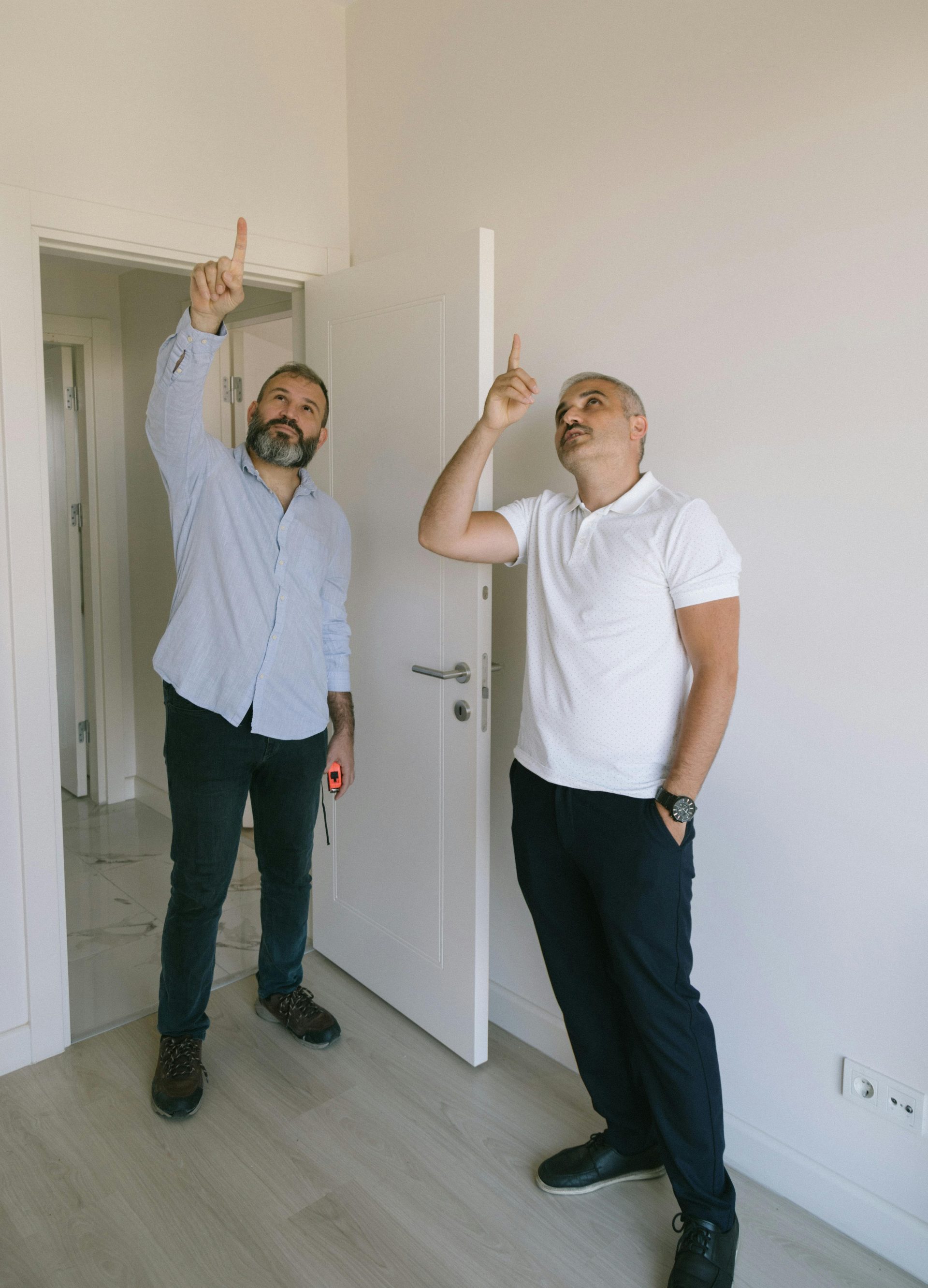 Two adult men pointing and examining interior details in a modern İstanbul apartment.